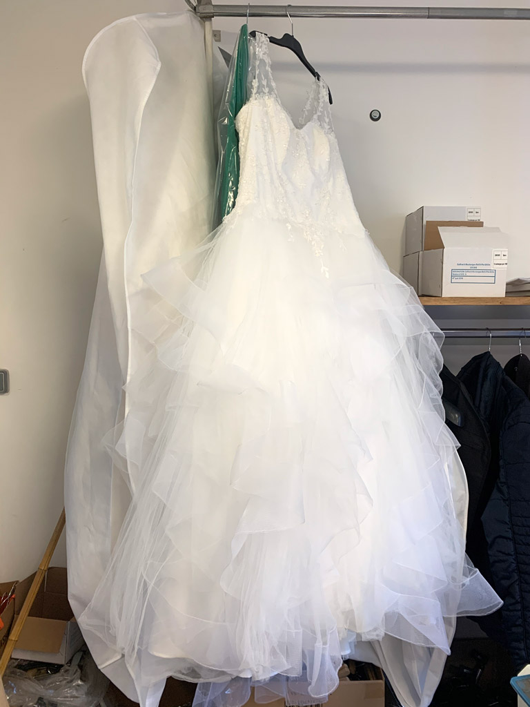 PRESSING 7 à sek à Savigneux - Robe longue de mariée d'un blanc éclatant avec dentelle, motifs à fleurs très fin sur un cintre avec ça housse de rangement